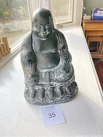 Front view of seated black ceramic Buddha figurine with hand-painted white and gold details.