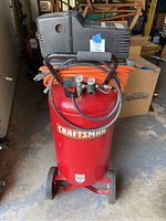 Front view of red Craftsman compressor tank with black motor housing and orange hose
