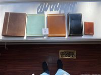 Four leather-bound photo albums and guest books of various sizes and colors displayed on a white surface.