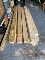 Photo depicting stacked 2x6 lumber boards on a concrete floor with varying lengths mostly between 7 to 8 feet. Some boards show signs of having one end cut at an angle.