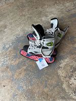 Pair of Mission child hockey skates with blade covers placed on the ground
