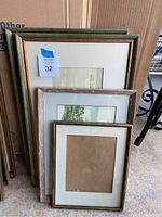 Four stacked picture frames of various sizes including two green matching frames, one distressed wood frame, and one smaller gold-trimmed frame.