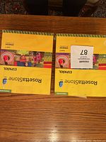Two boxed Rosetta Stone Spanish language kits for Level 1 and Level 2, placed side by side on a wooden table, showing front covers with yellow backgrounds and colorful images.