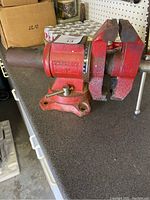 Side view of the red Roughneck 5-inch bench vise showing the swivel base and mounting holes.