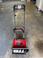 Front view of Toro electric snow blower with model ES-120 label visible, showing handle and auger area.