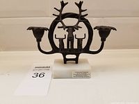 Front view of the bronze ceremonial standard on white marble base with label and a hand for scale.