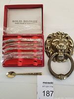 Photo of the boxed set of six solid bronze spoons and the brass lion head door knocker with ring.