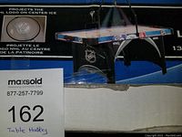 Boxed NHL Electric Air Hockey Table with image showing the NHL logo projected on center ice in the design.