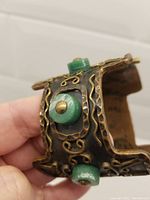 Close-up showing the bracelet's copper plating, green stones, and brass wire decoration.
