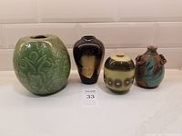 Four unique pottery vessels displayed together on a white surface.