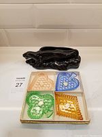 Black ceramic jaguar planter and box containing 4 playing card suits glass trinket dishes: pink heart, blue spade, green club, amber diamond.