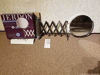Jerdon wall mount extension mirror fully expanded next to its box showing the product and packaging