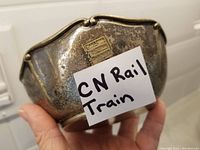 Silver plated bowl held by hand showing its size and CN Rail notation on paper for identification