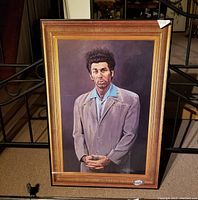 Framed painted portrait of a man with distinct hair and clothing, identified as Cosmo Kramer from Seinfeld, standing against a brownish backdrop.