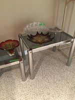 Four glass bowls displayed on mirrored accent tables; two clear glass bowls and two colored glass bowls (amber and reddish).
