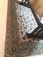 Rug under dining table showing cream field and green floral border