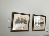 Two of the three framed circular art prints hanging on a white wall showing winter and riverside tree landscapes.