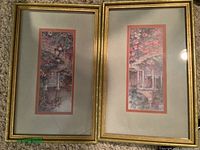Two matching Windsor Decor garden prints in gold frames with double mats showing garden scenes with white fences and flowers.