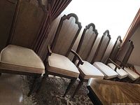 Full set of six mahogany dining chairs in a row, showing four side chairs and two captain's chairs with armrests, placed in a room with rug and curtains.