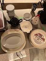 Overview of the lot showing all items on a table including teapot, bowls, platters, canister, and ceramic jar