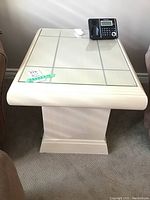 Square wood pedestal base end table with mirrored glass top and light wood finish, size sticker on glass shows 28x22x22 inches.