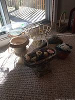 Overview of the six assorted pots and faux flowers arranged on carpet near glass door, including urn-shaped pot, wooden planter with flowers, glass pedestal bowl, and two small flower pots.
