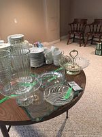 Photo of five assorted glassware pieces including platters, bowl, cake stand, and serving dish on a wooden table
