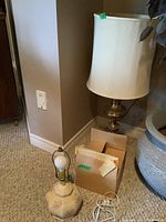 Brass table lamp with cream fabric shade positioned next to boxes.