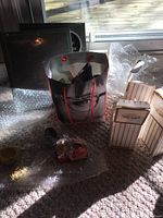 Four trinket holders packed in protective bubble wrap with additional boxed items and bag with eyeglass holders