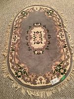 Full oval wool area rug laid out on carpeted floor, showing entire pattern and fringe edges.