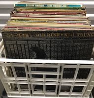 Photo showing a side view of over 50 vinyl records in storage crate, covers include varied classic album artwork.