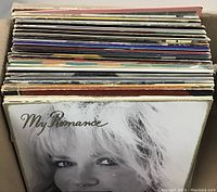 Top view of stacked vinyl record albums showing varied album cover edges and thicknesses