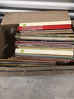 Box filled with over 40 vinyl records showing tops of album covers and sleeves