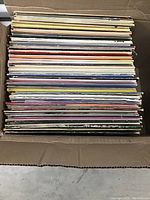Top down photo showing the packed box of more than 50 vinyl records in their sleeves, various colors and thicknesses.