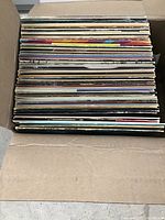 Box filled with over 40 vinyl records with visible spines showing various colors and labels.