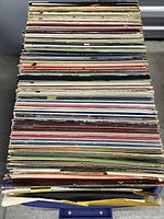 Top-down view of a large stack of over 40 vinyl records with diverse colored covers.