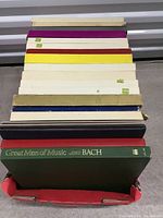 View of stacked vinyl records showing various colored sleeves with the Great Men of Music Johann Sebastian Bach box set on top.