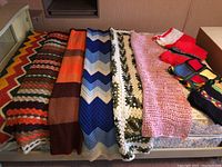Top view of ten afghans laid out showing different colors, sizes, and crochet patterns.