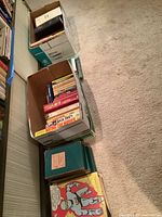 Photo showing boxes of various books from side perspective, titles visible on top