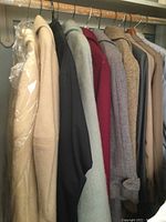 Row of assorted men's and women's wool coats and blazers on hangers showing a range of colors and textures.