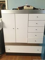 Front view of white Singer Furniture dresser showing cabinet and drawers with silver knobs