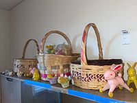 Photo showing all three woven Easter baskets with various vintage bunny and chick figurines and Easter decorations arranged on a shelf.