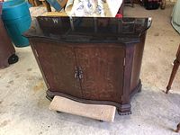 Full front view of the curved cherry wood cabinet with black granite top and floral design on doors.
