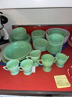 Wide view showing stacked dinner plates, bread plates, bowls, small creamers on countertop