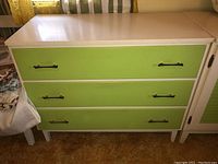 Front view of the MCM wood chest showing three green drawers with metal handles and white frame.