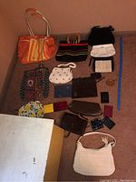 Full view of assorted purses, card holders, and tote bags including orange tote bag, patchwork fabric bag, multiple small wallets and purses in various colors and styles.