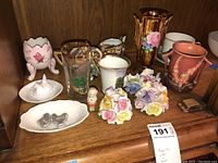 Wide shot of all items showing Roseville vase, Noritake creamer and sugar bowl, Thomas Kinkaid tea cup and more.