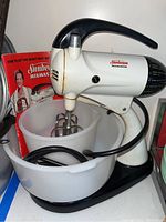 Vintage Sunbeam Mixmaster stand mixer with two plastic mixing bowls and beaters, cord wrapped around base