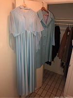 Full view of vintage light blue formal dress on hanger with matching coat behind it in closet