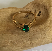 Front view of ring showing oval green garnet in prong setting on yellow gold band
